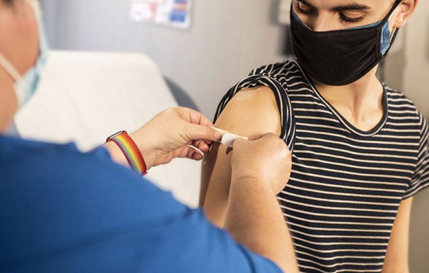 A masked person getting a bandage after getting a shot