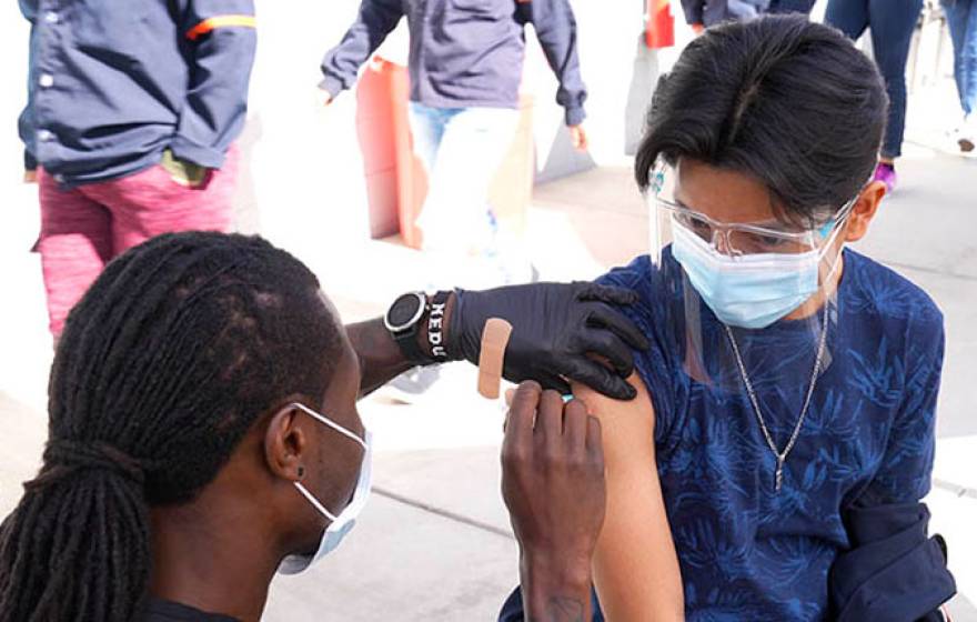 A worker receives a shot from a nurse