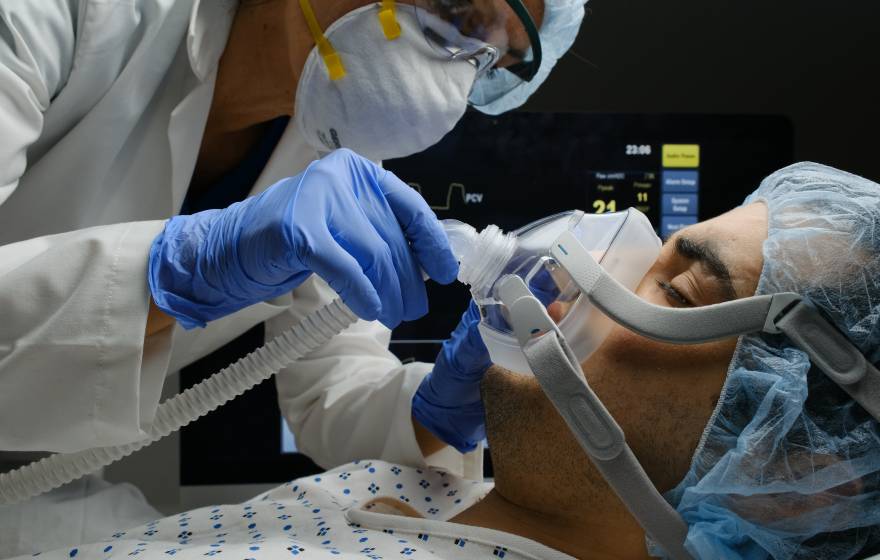 A COVID-19 patient on a ventilator being checked by a doctor