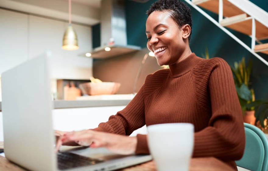 Young black woman laughing while looking at computer screen