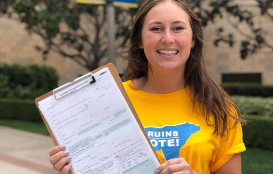 Young woman with Bruins Vote T-shirt holds up voter registration form