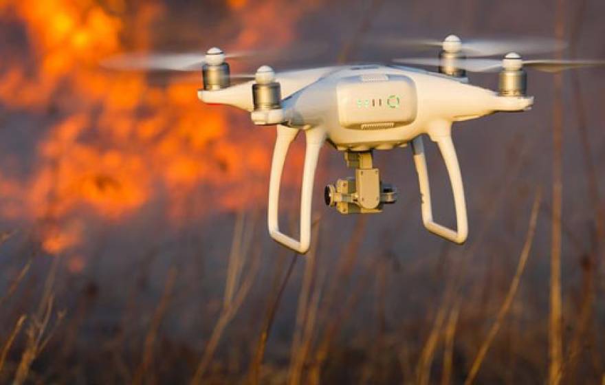 A drone with wildfire in the background