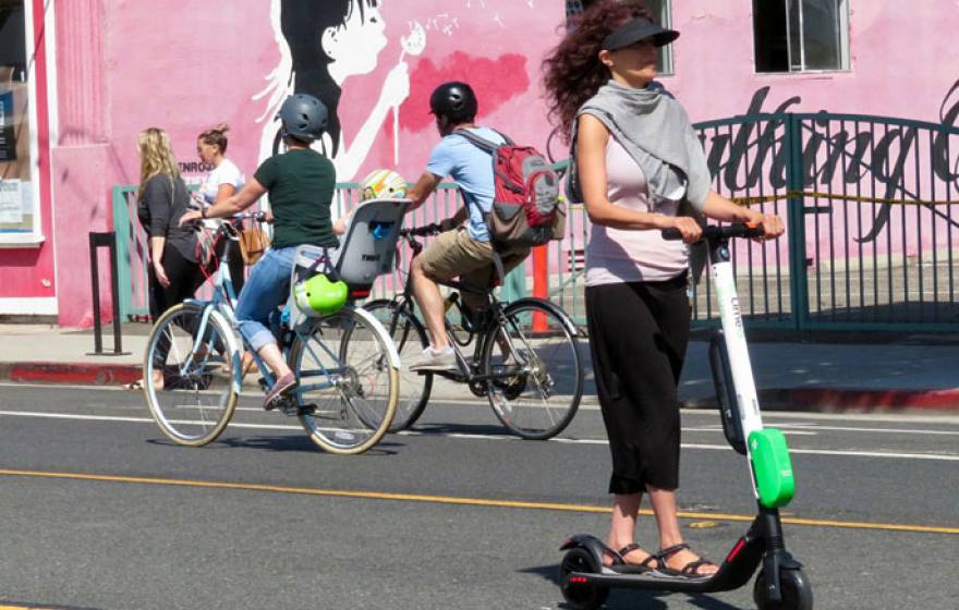 A woman rides a Lime scooter on the street in Santa Monica