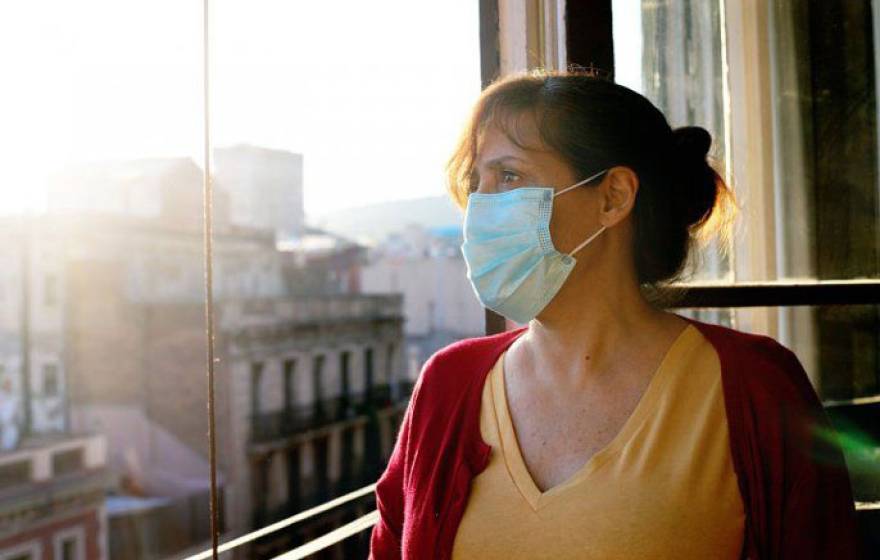 Woman in mask looks out the window