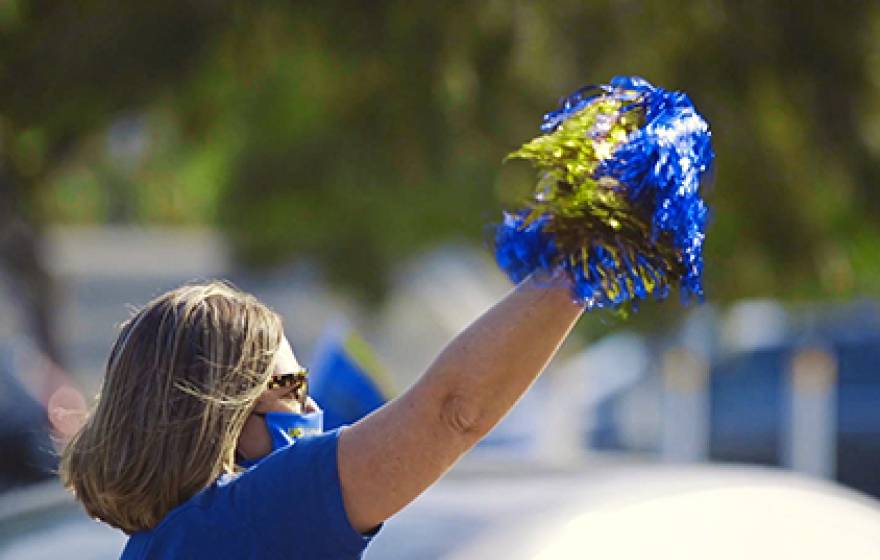 Woman with a pom-pom and a mask cheering