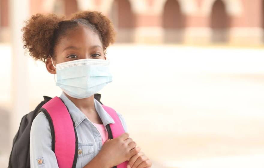 Young Black girl with a backpack in a mask