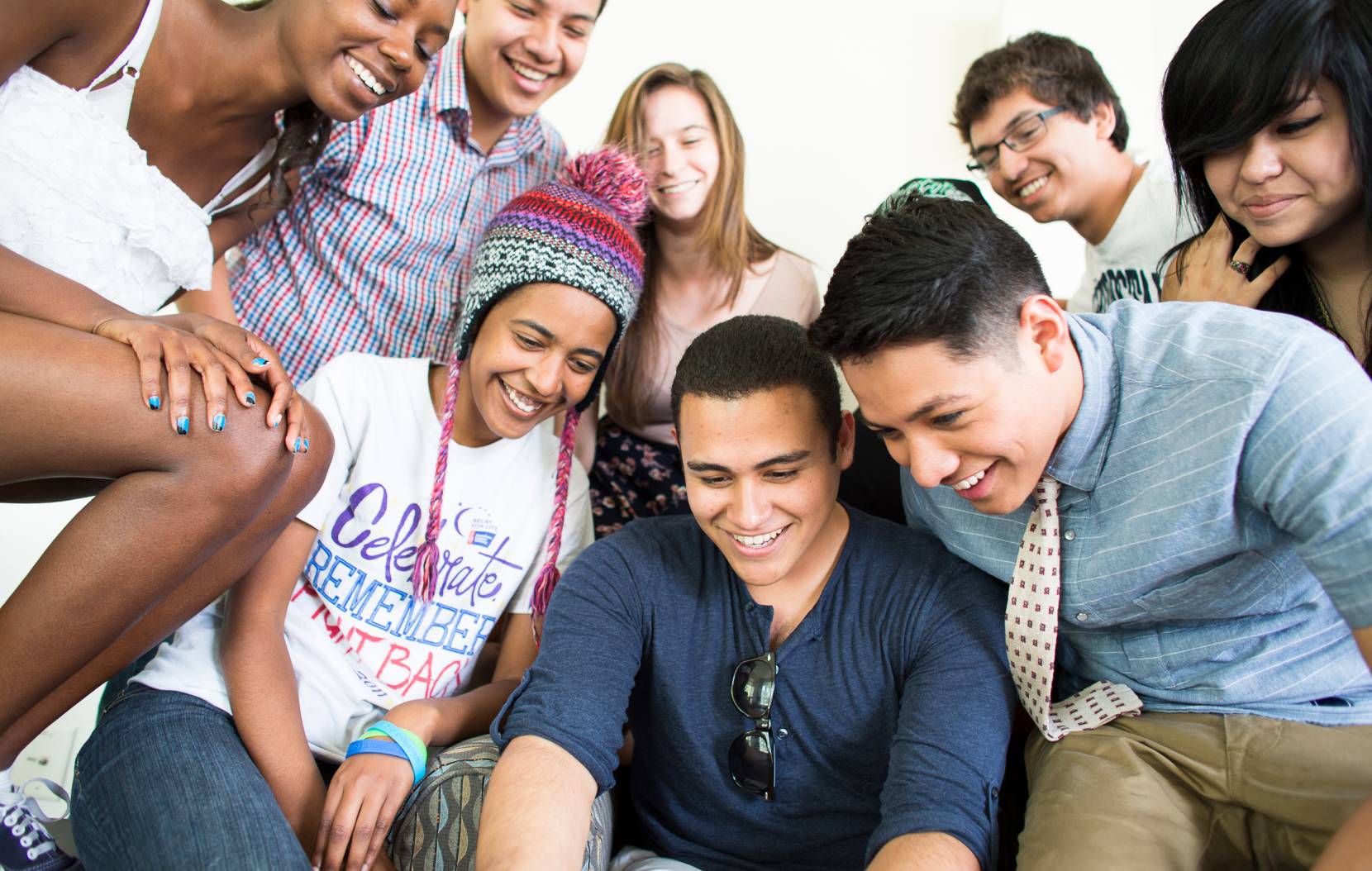A diverse group of students stare at something down and out of frame, likely a computer