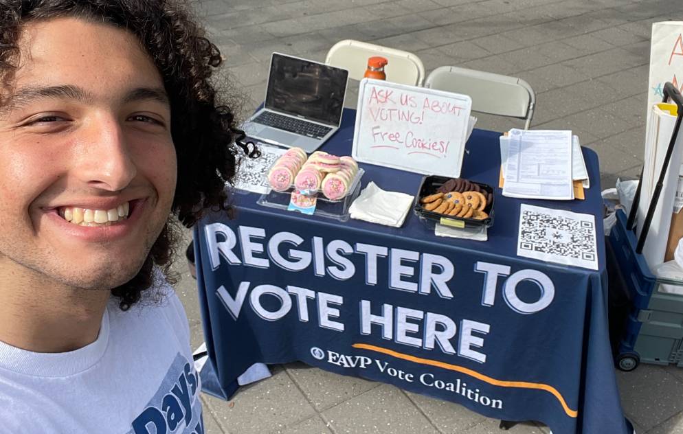 Alex Edgar does a selfie while in front of a voter registration table