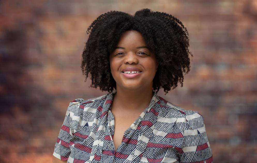 Christine Head smiles at the camera against a brick backdrop