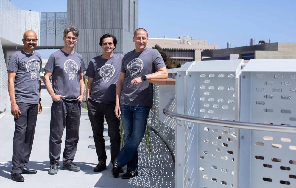 Four men in matching shirts stand together outside on the UC Santa Barbara campus
