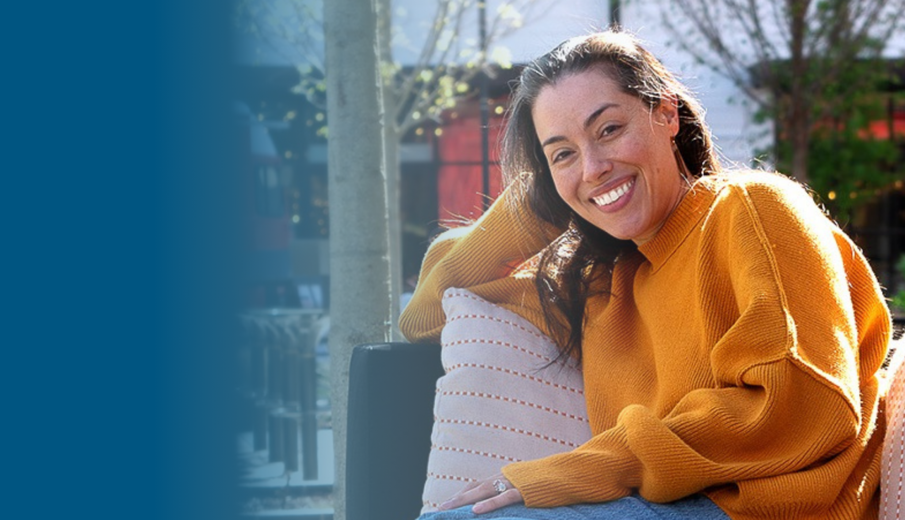 Rosa W. Everson, young Latina woman, relaxing at UC Santa Cruz, smiling in orange sweater