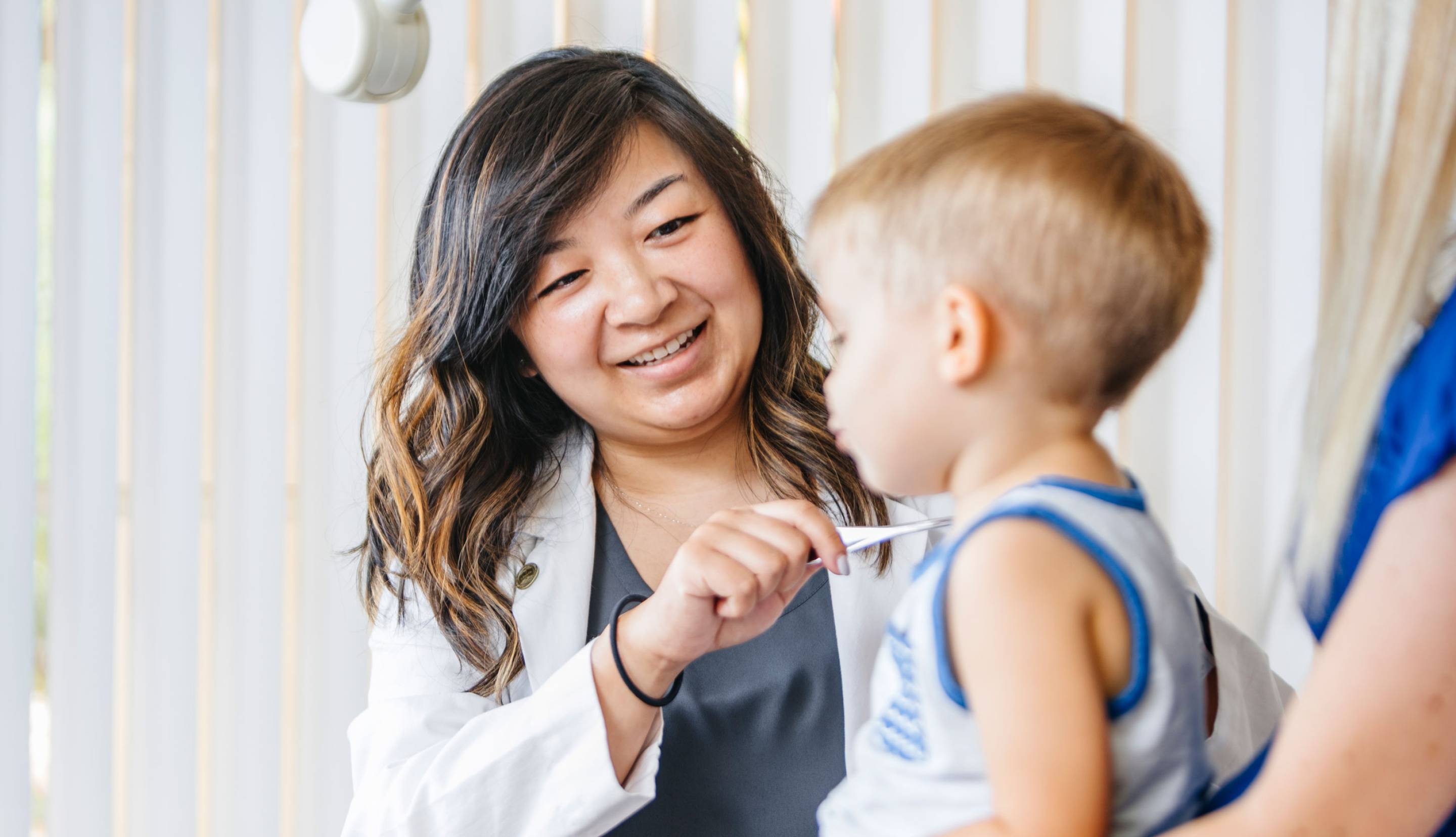 A pediatrician smiles at a young boy in a clinical setting.