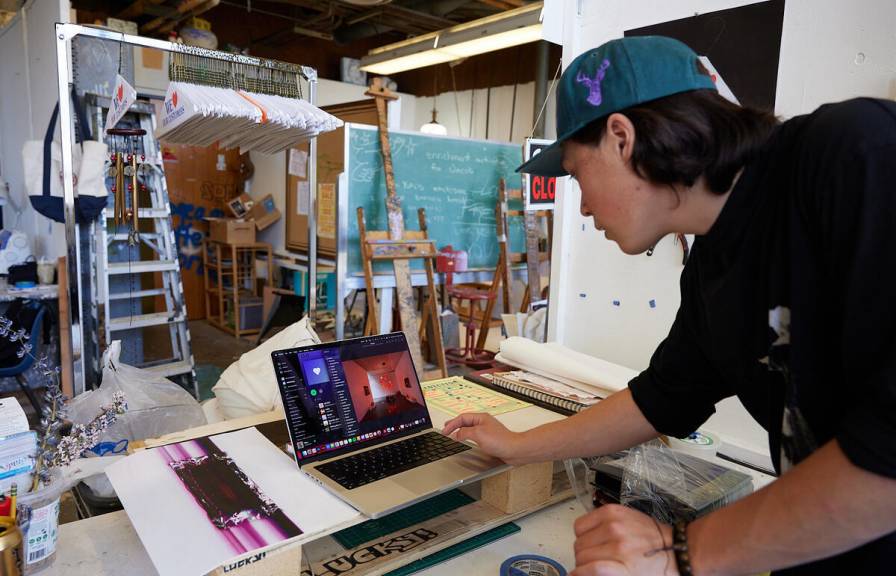 Student working on a laptop in an art studio. 