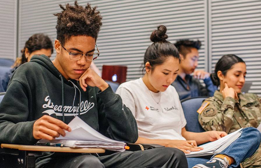 Students sitting in a classroom focused on reading during a lecture.