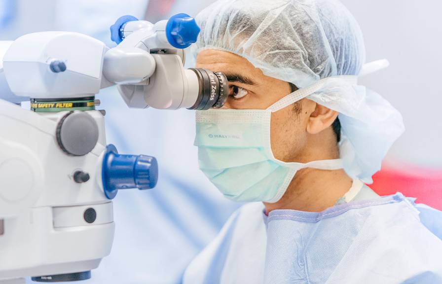 Researcher looking into a microscope