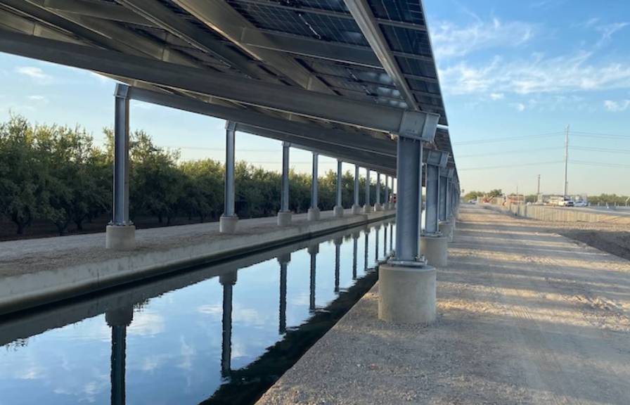 A canopy covers a canal next to a roadside blue sky behind