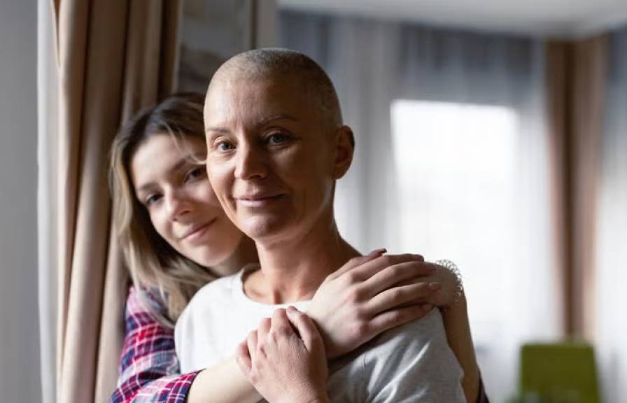 A woman puts her arms around another woman who has no hair