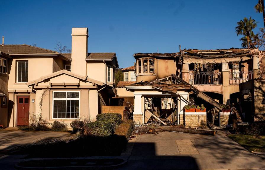 A house ravaged by wildfire next door to a house that escaped unscathed