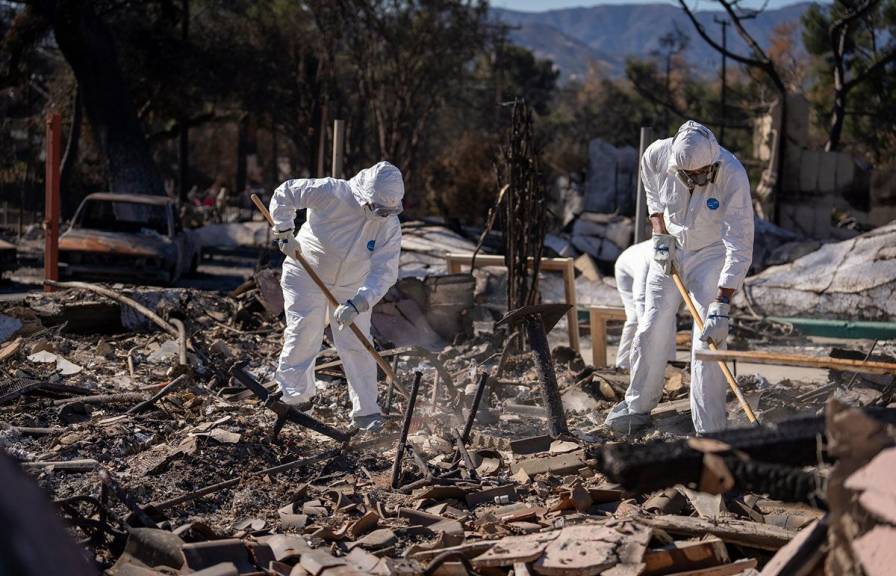 People wearing hazmat suits digging through fire debris from burned buildings
