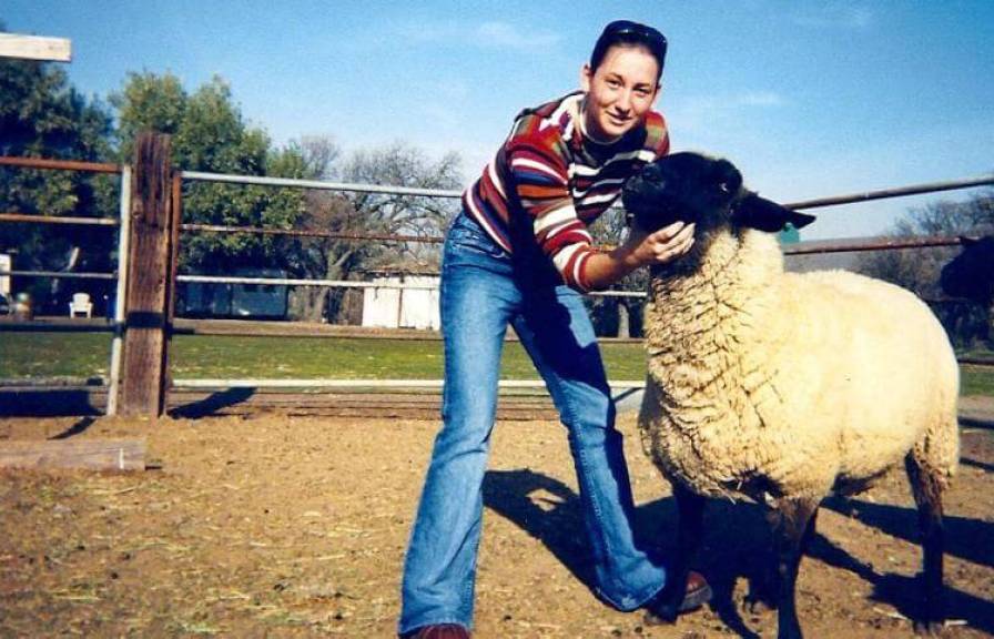 A young woman next to a sheep in a paddock