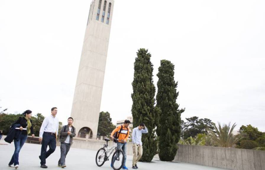 Students walking on campus with a large white tower in the background.