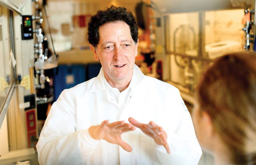 Kevan Shokat in a white lab coat speaking to a grad student in a lab.