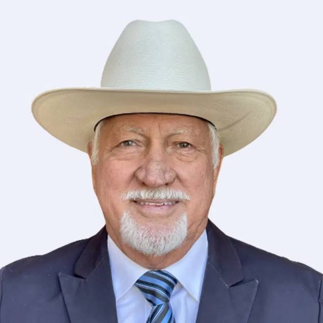 Man with white goatee and a white cowboy hat smiles in a suit