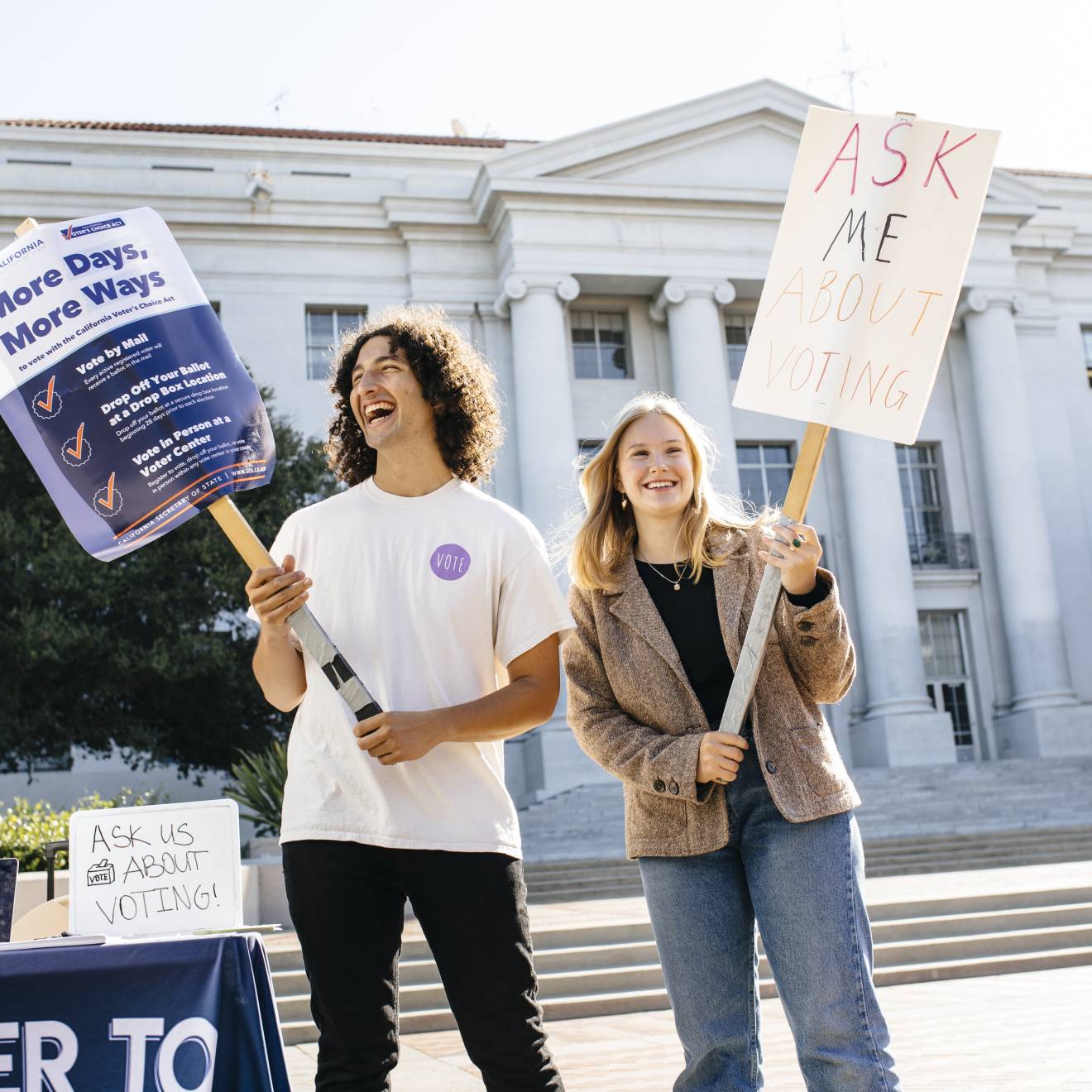Students Alex Edgar and Skylar Betts hold signs about voting on Sproul Plaza