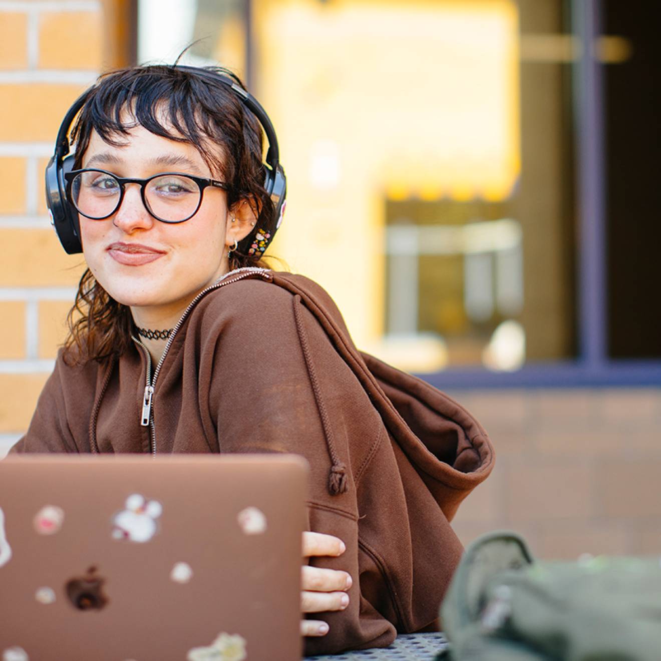 a student sits with an open laptop, smiling