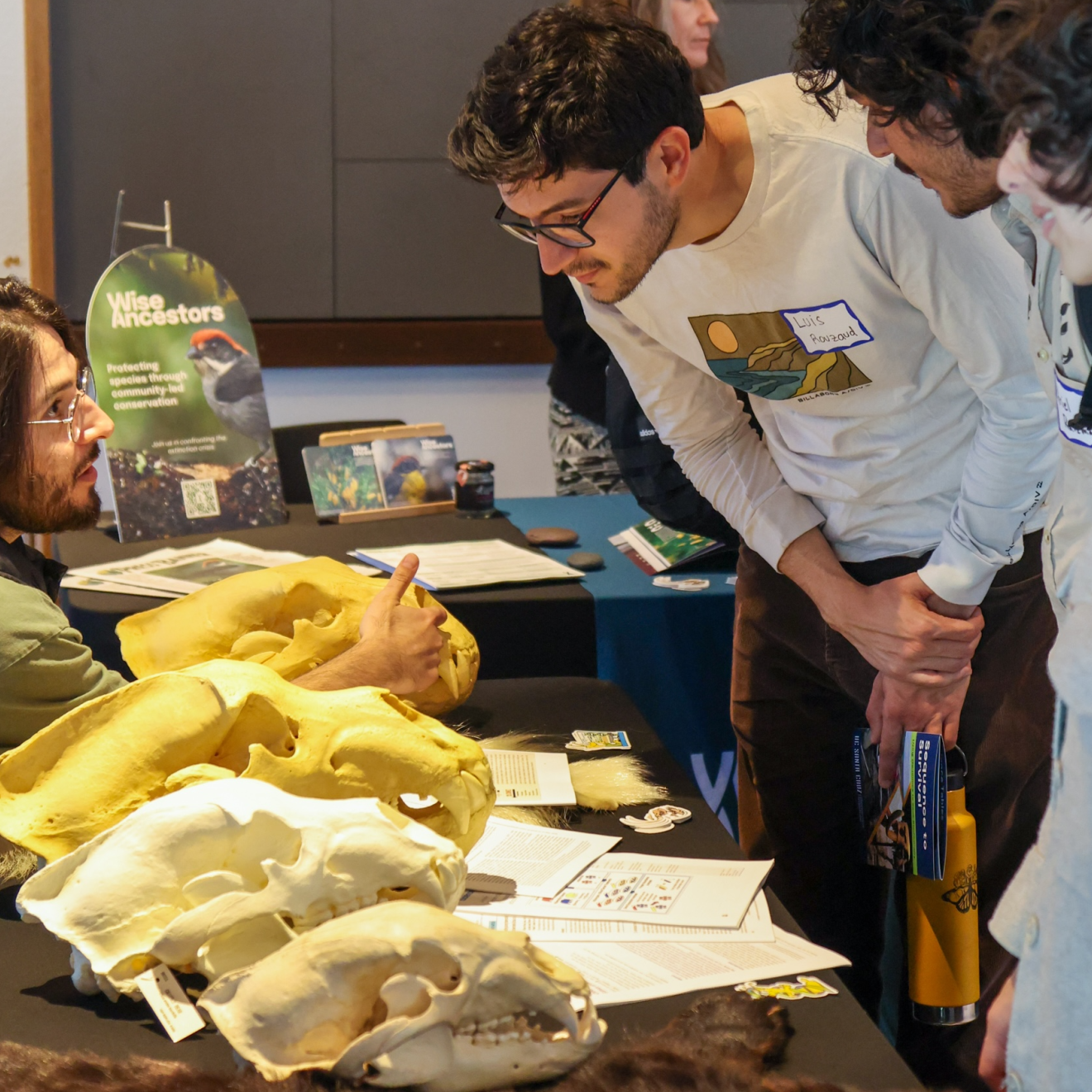A man talking to students visiting a table that is displaying bear skulls