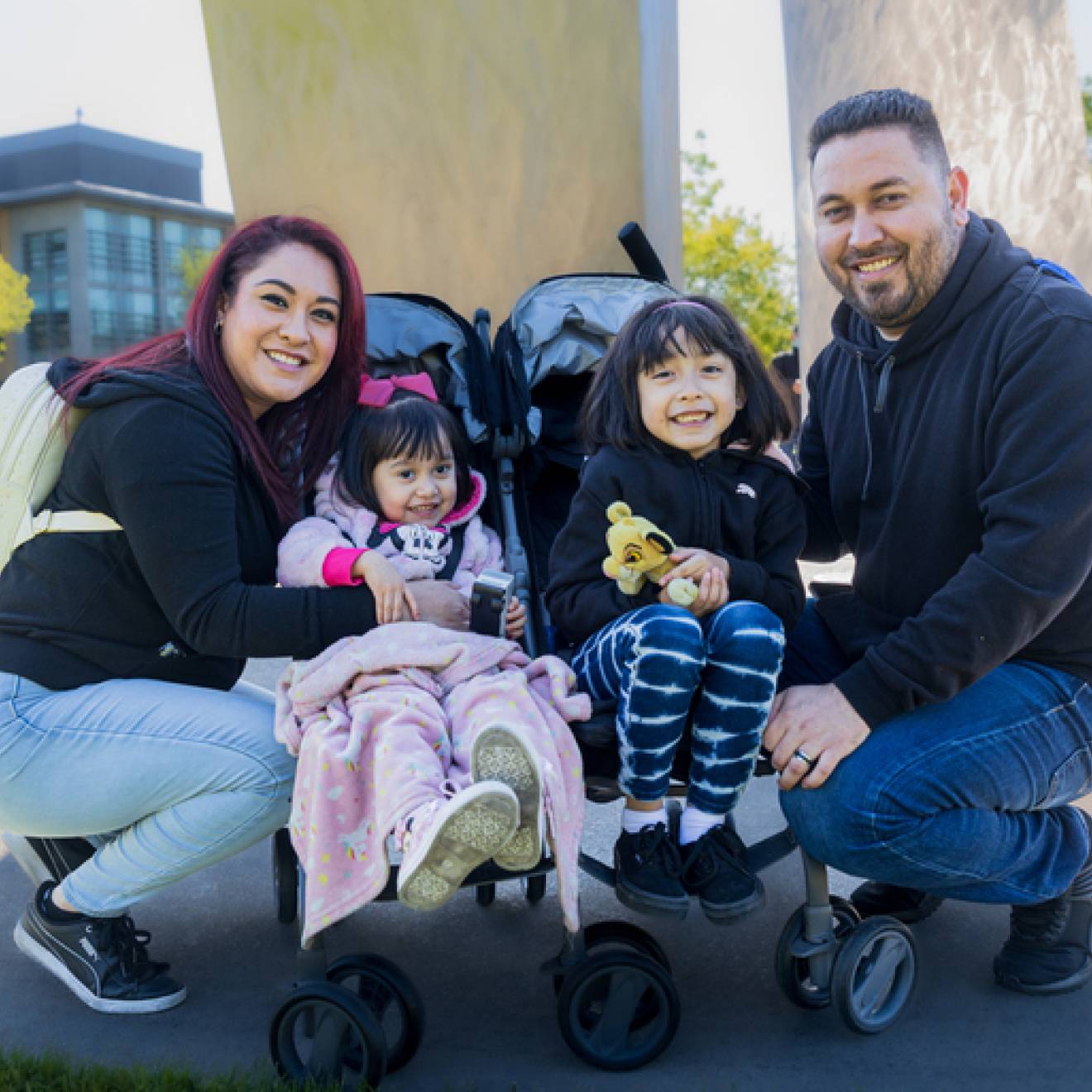 A family with two parents and two young children in a stroller