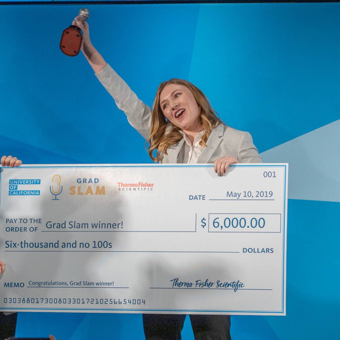 2019 Grad Slam winner Katie Murphy cheers with her trophy and giant check