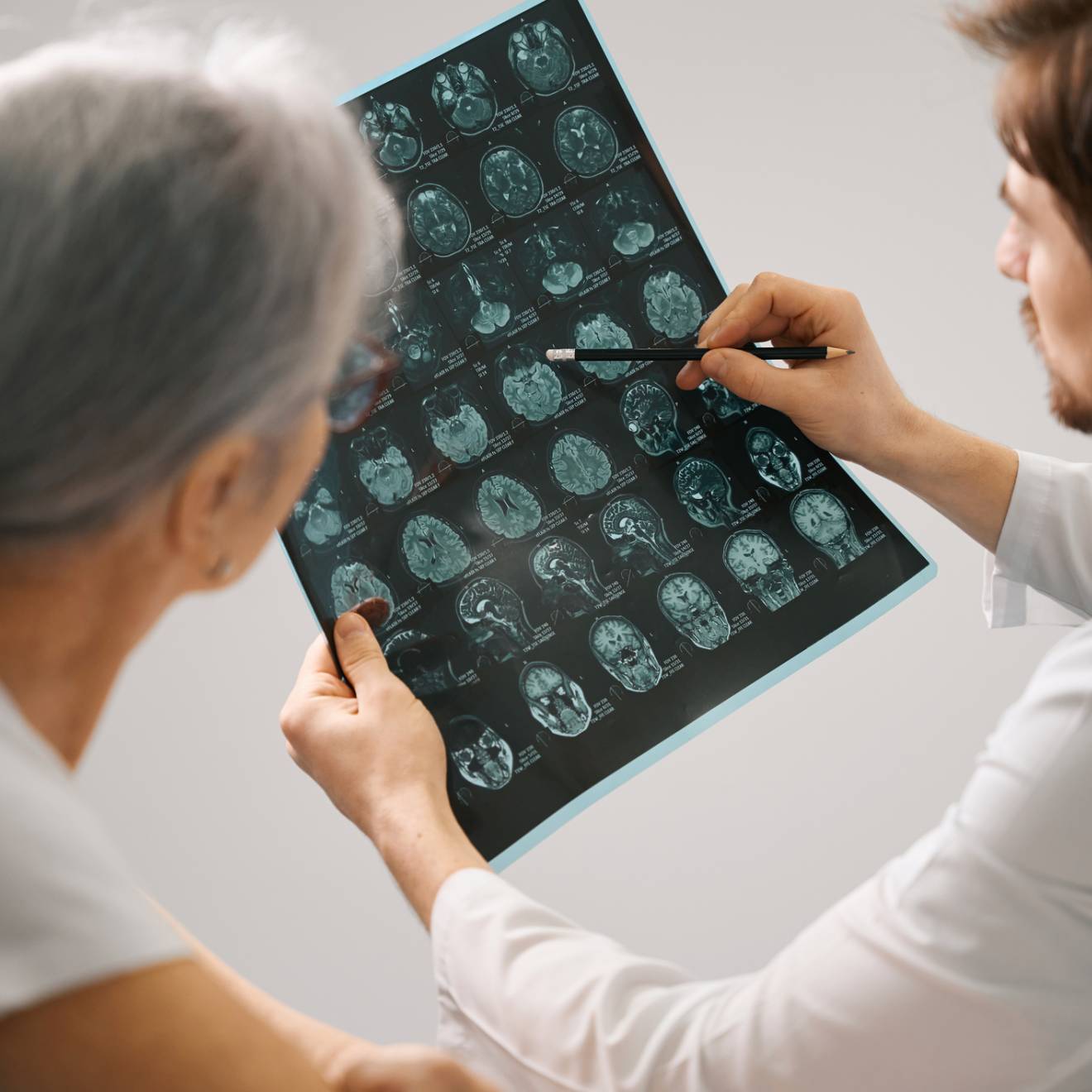 Doctor diagnostician holds an MRI scan of the brain in his hands, he consults an elderly lady