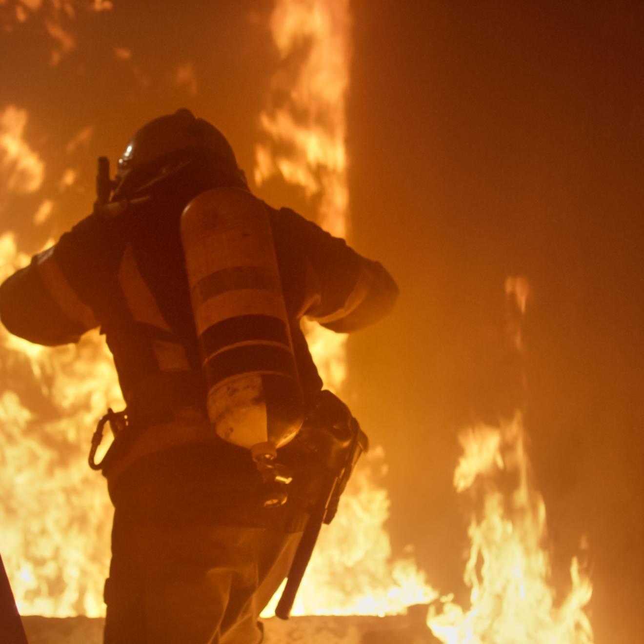 A firefighter with an oxygen cylinder runs up stairs on fire