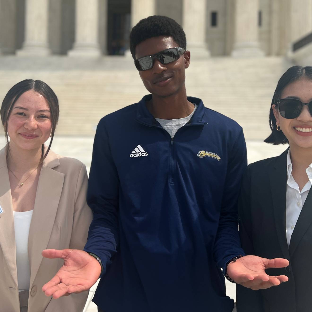 3 UCAN student ambassadors in business attire smile in front of the Capitol Building