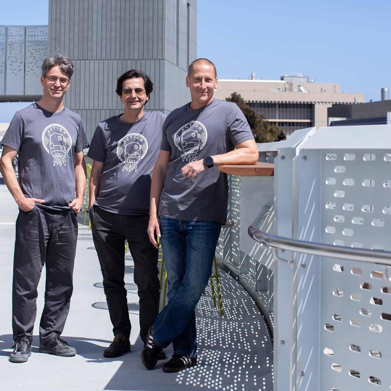 Four men in matching T-shirts standing outside