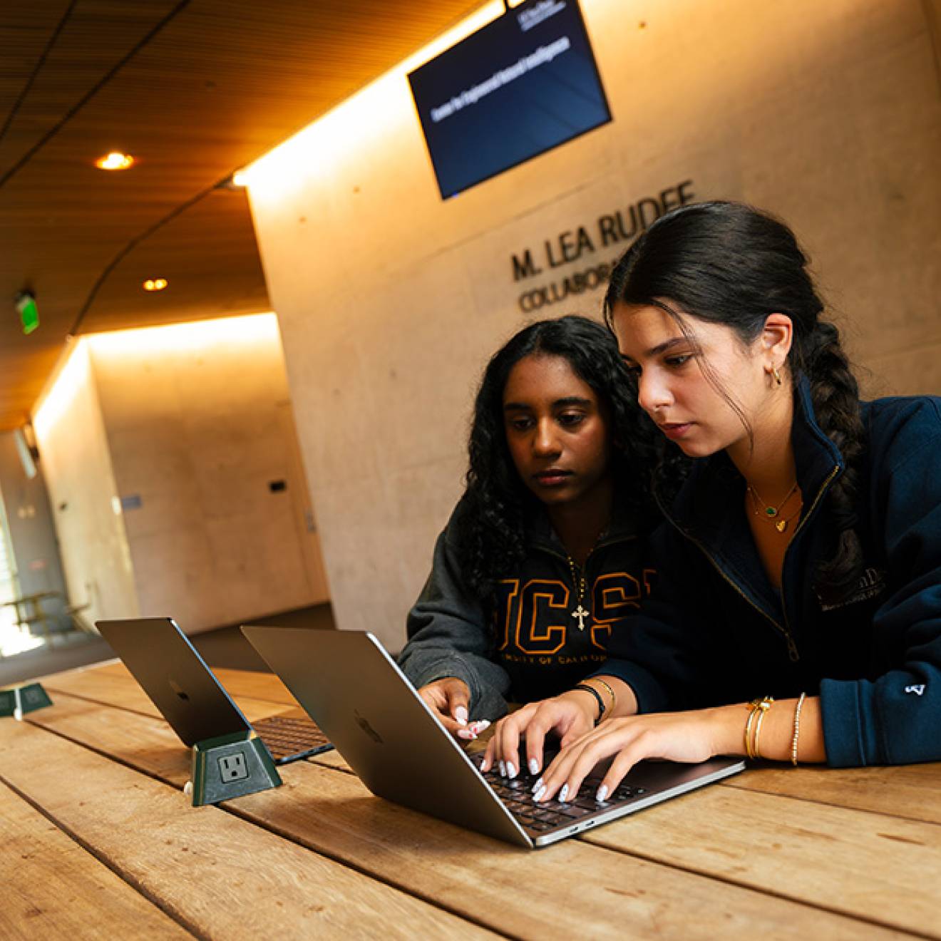Two young women sit together looking at a computer