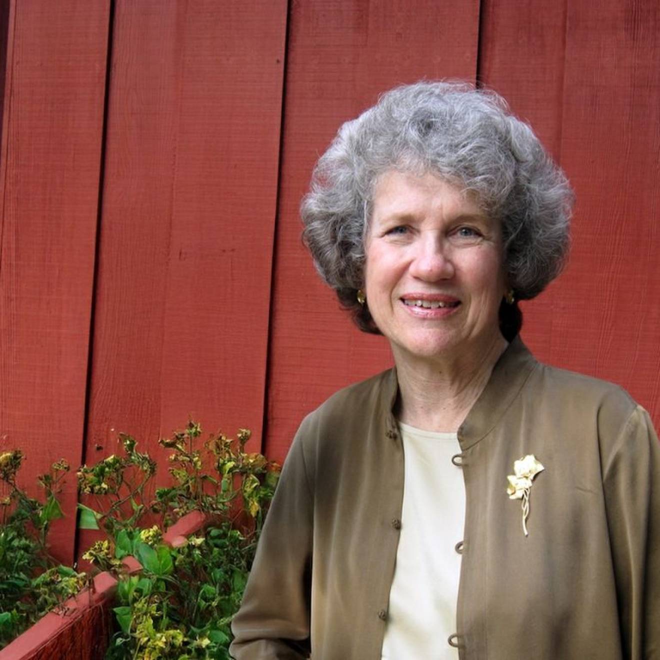An older woman smiles in a portrait outside