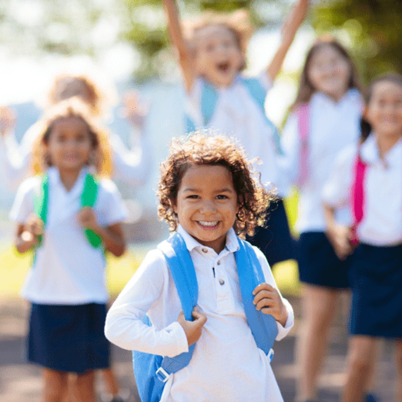 Interracial group of children of mixed age run and cheer on the first day of new academic year.