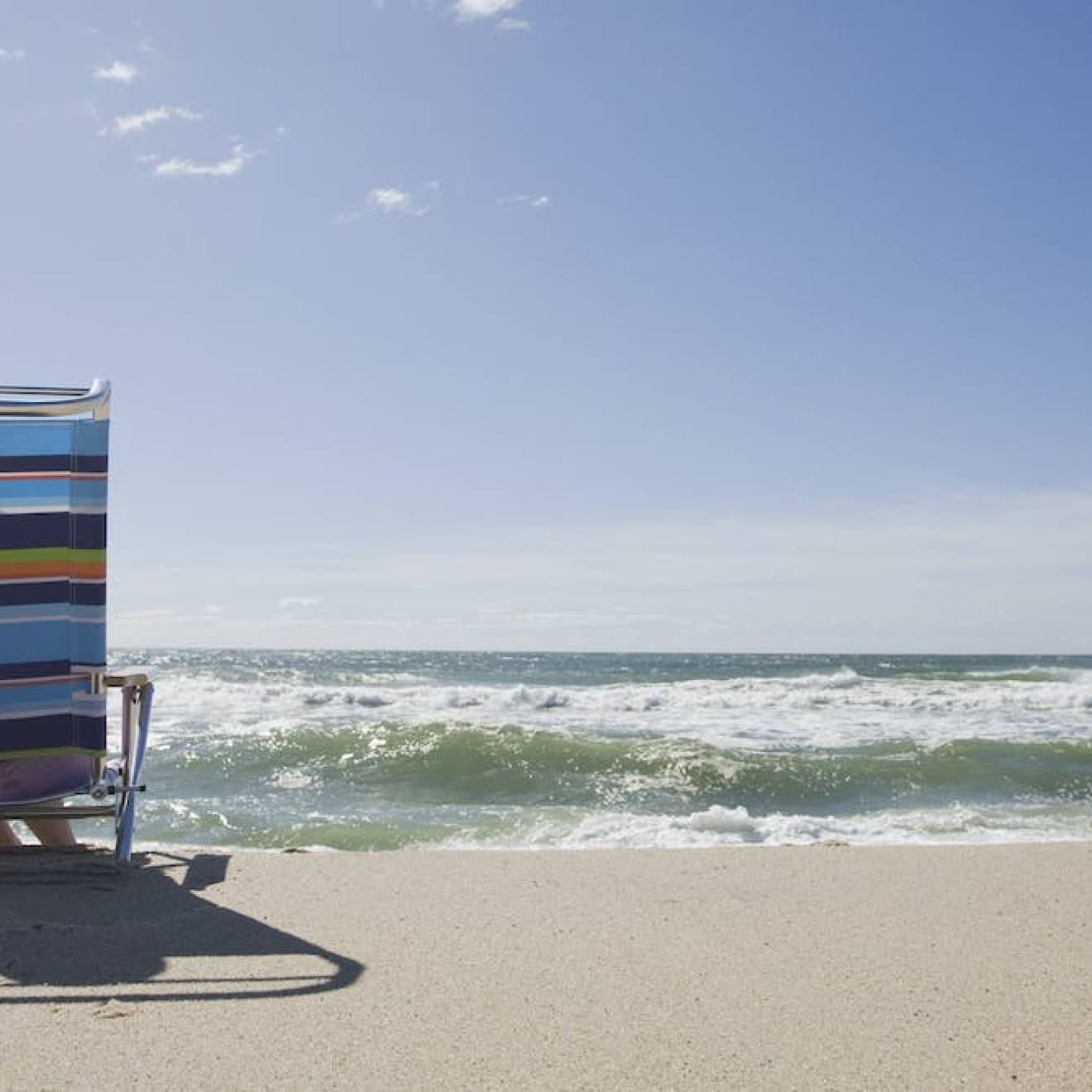 Person reading on the beach, photographed from the back with the ocean in front
