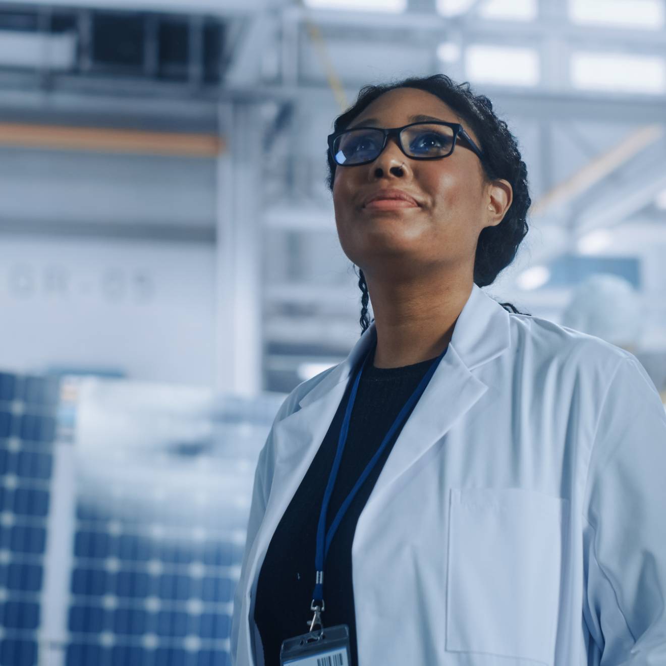 Black woman scientist looking up in a warehouse