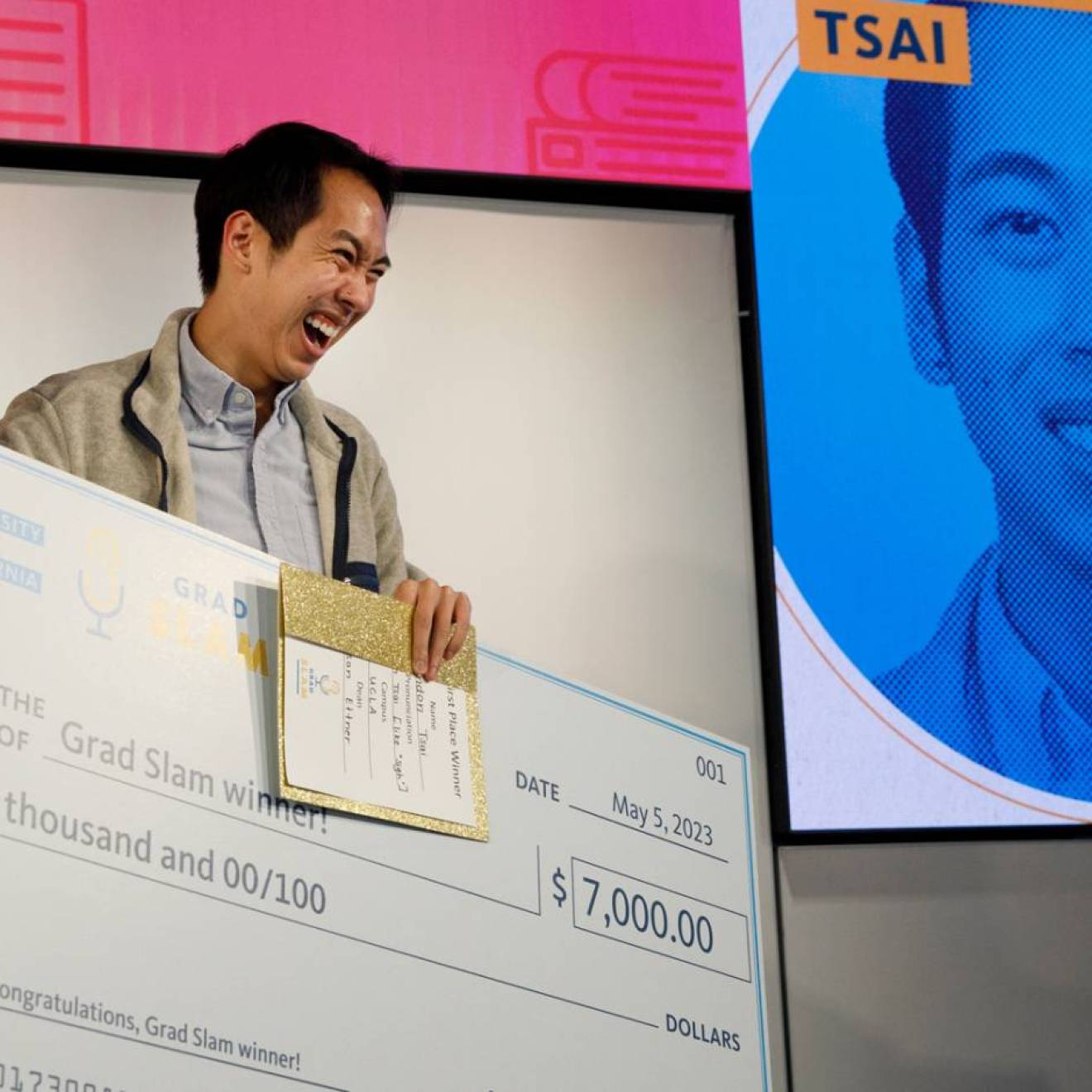 A man smiles while holding a trophy and a giant check for $7,000