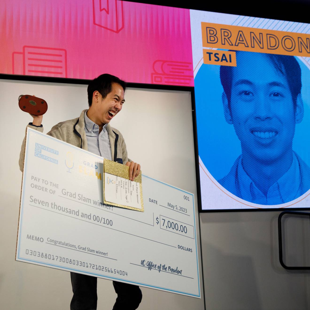 Brandon Tsai holds up the trophy, the Slammy, and his winning check at UC Grad Slam 2023