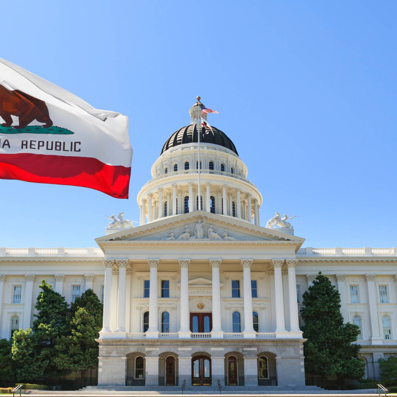 Sacramento capitol building with California state flag flying in front of it
