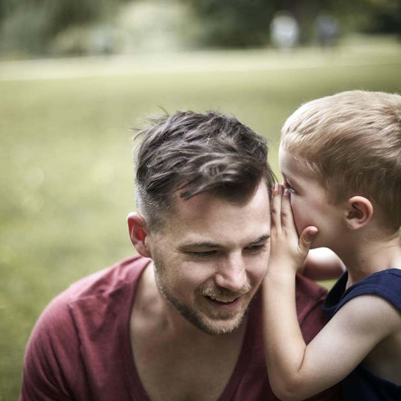 Child whispering in father's ear