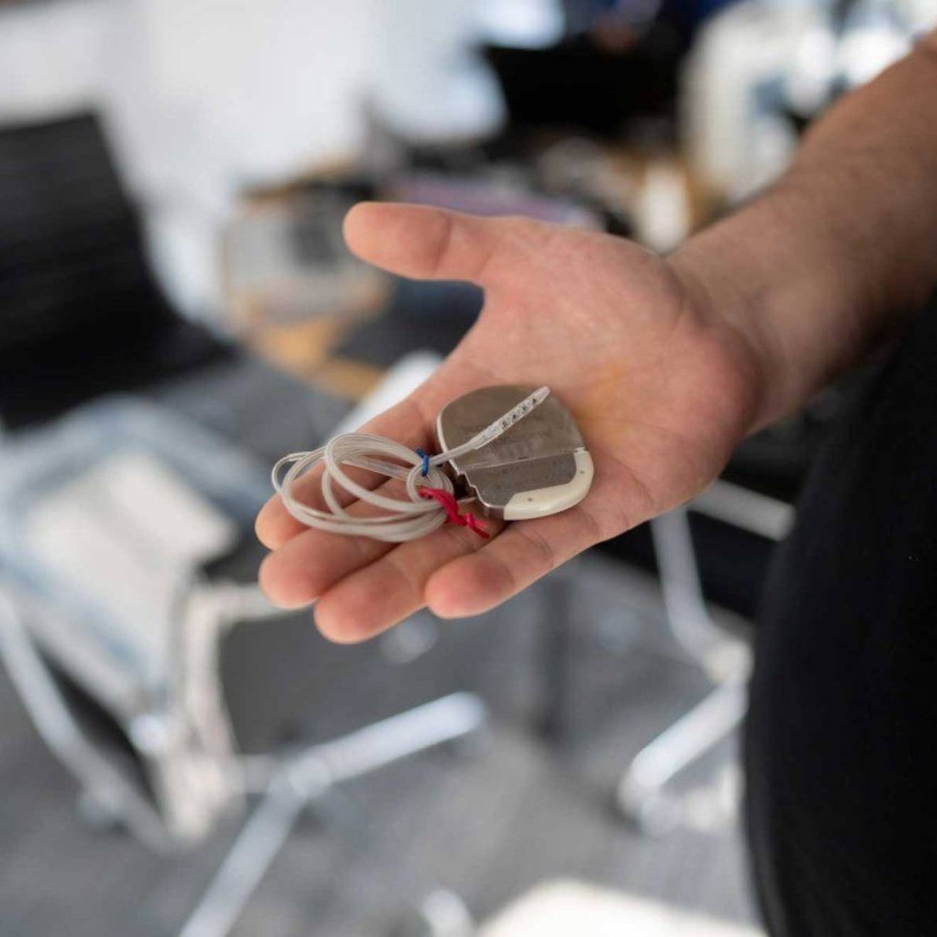A patient holds a deep brain stimulation device in his hand.