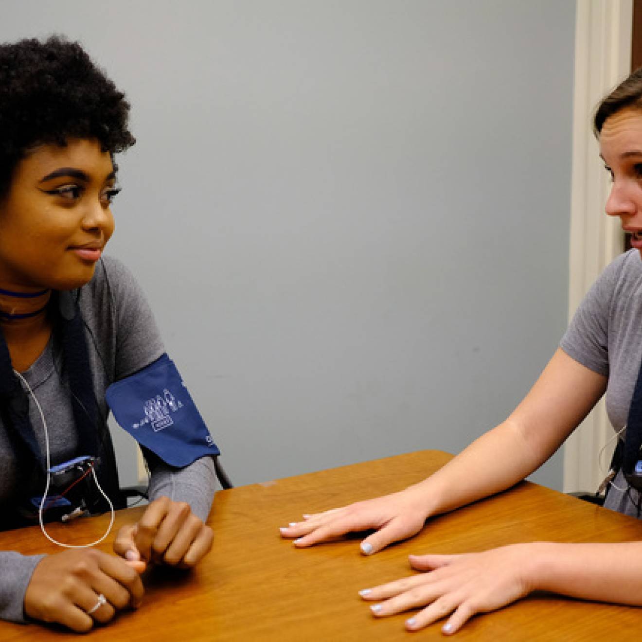 Two young people in blood pressure cuffs talking