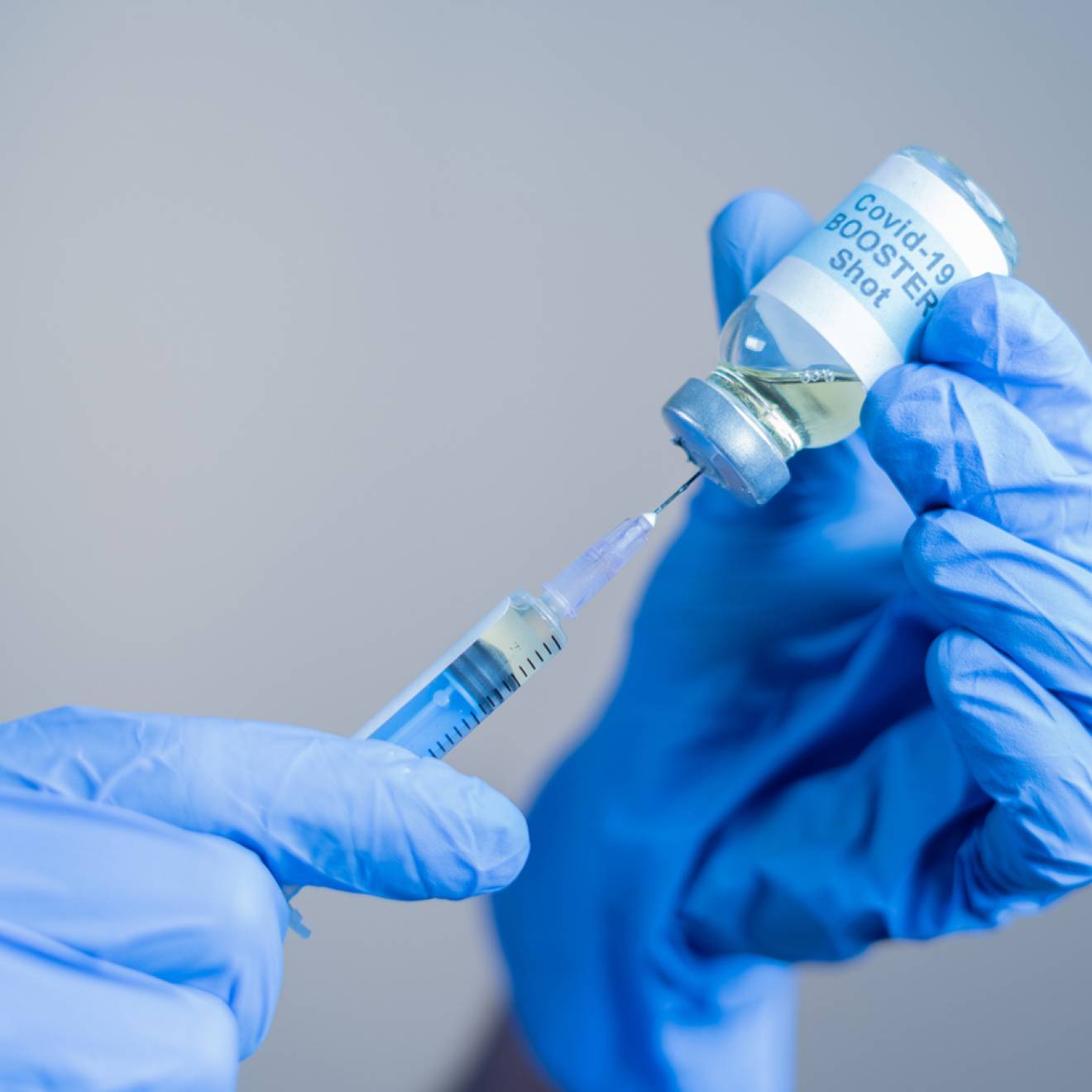 Close up of doctor or nurse's hands preparing to administer a COVID-19 booster shot