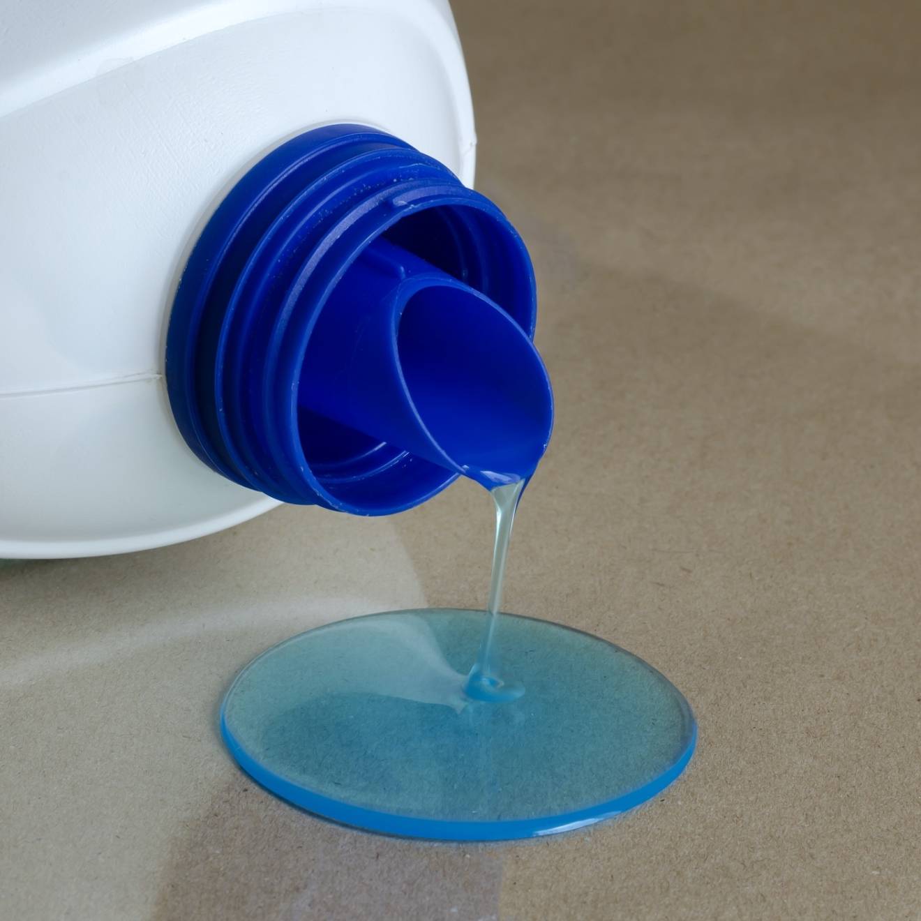 blue liquid spilling out of a plastic laundry detergent bottle