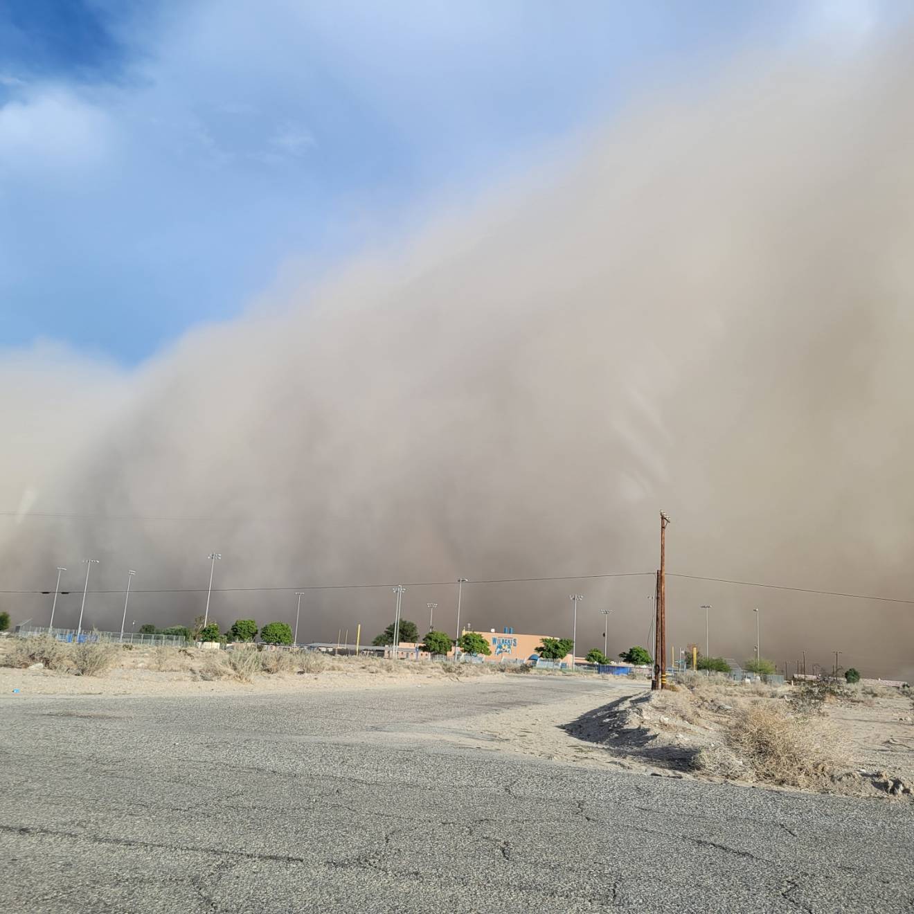 A dust cloud, taking up most of the picture, over a dirt road